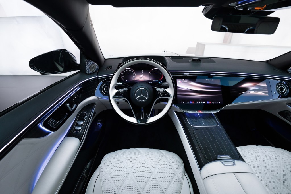 Interior of the Mercedes-Maybach S-Class, featuring a white steering wheel, digital dashboard, and infotainment screen.