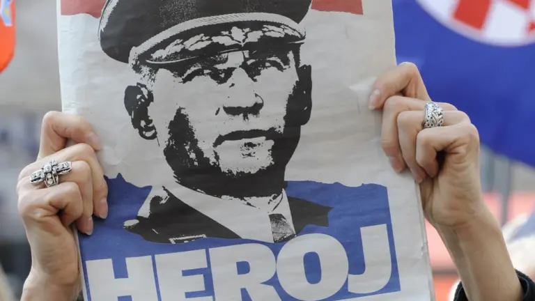 Një grua mban një gazetë me portretin e gjeneralit kroat, Ante Gotovina, ku shkruan “hero”, ndërsa ndjek transmetimin e drejtpërdrejtë televiziv të aktgjykimit ndaj tij. Zagreb, 15 prill 2011.