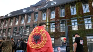 Një protestues i mbështjellë me flamur të Ushtrisë Çlirimtare të Kosovës, qëndron pranë selisë së Dhomave të Specializuara të Kosovës në Hagë, teksa gjykatësi shqipton aktgjykimin ndaj ish-krerëve të UÇK-së, në Hagë, Holandë, 16 shtator 2026.